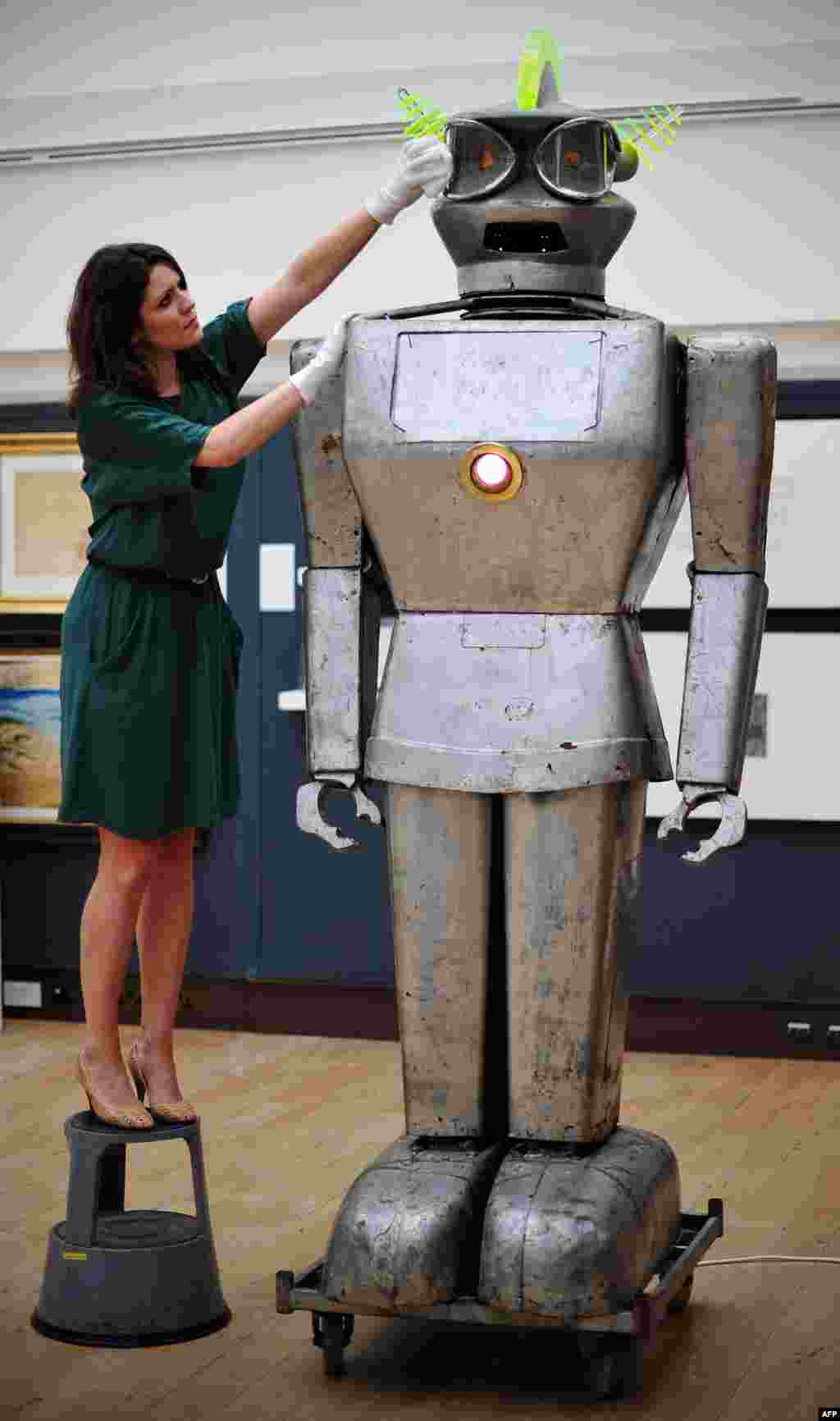 Seorang anggota staf rumah lelang Christie's di pusat kota London, Inggris berpose dengan sebuah robot yang disebut 'Cygan'. Cygan merupakan salah satu robot tercanggih pada masanya, yang memiliki kemampuan untuk menerima perintah yang diucapkan dan merespon cahaya. (AFP PHOTO / CARL COURT)