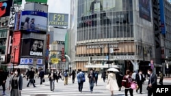 Para pejalan kaki di penyeberangan jalan Shibuya, Tokyo, mengenakan masker di tengah pandemi corona, 28 April 2020. (Foto: dok).