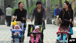 FILE - Women push babies in prams through a Beijing park during a public holiday, April 5, 2011.