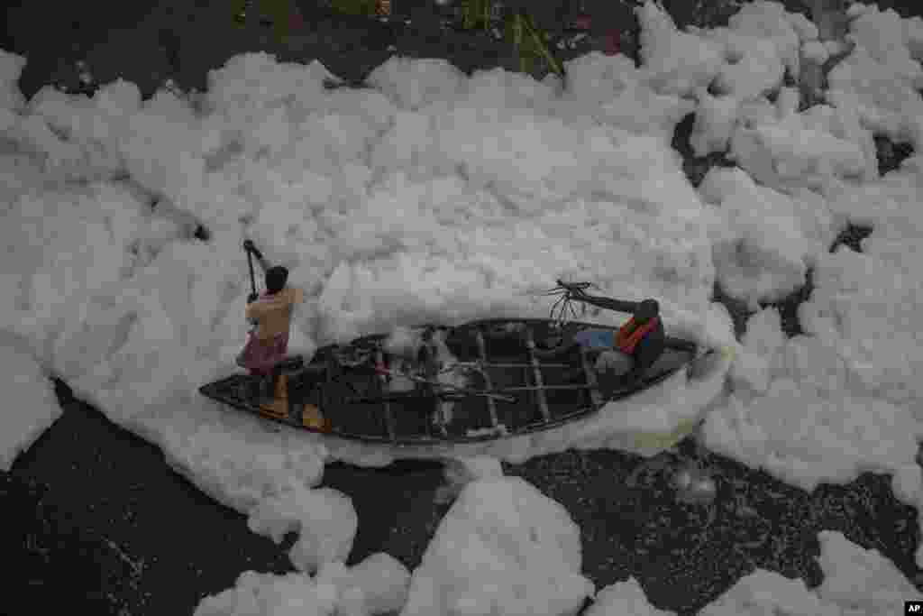 A man rows a boat in the Yamuna River, which is covered with a chemical foam caused by industrial and domestic pollution, during the Chhath Puja festival in New Delhi, India.