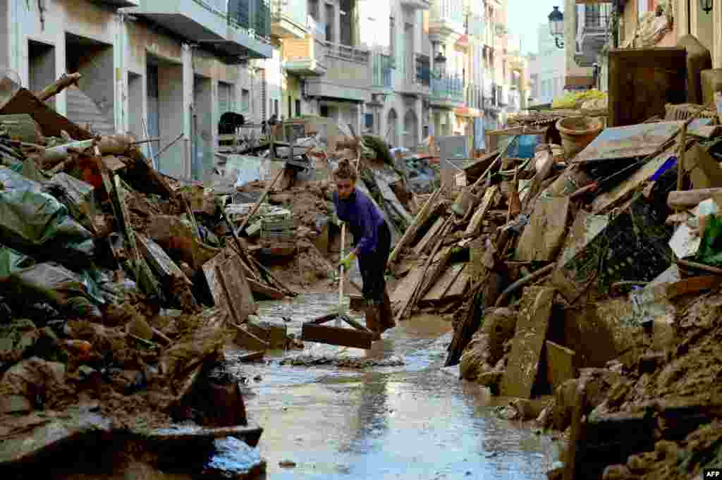 A woman cleans mud among debris in a street of Paiporta, south of Valencia, eastern Spain, in the aftermath of deadly floods. Spain announced an aid package worth 10.6 billion euros ($11.5 billion) to rebuild regions devastated by its worst floods in a generation that have killed 219 people.