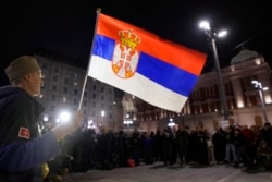 FILE - A man holds a Serbian flag during a rally, in Belgrade, Serbia, Nov. 28, 2021. Activists accuse Serbia's populist authorities of allowing foreign investors, mostly from China, to hurt the Balkan nation's environment in their search for profits.