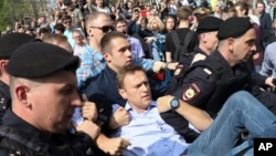 Polisi Rusia membopong kelompok oposisi Alexei Navalny (tengah), dalam sebuah unjuk rasa memprotes pelantikan Presiden Vladimir Putin di Alun-alun Pushkin di Moskow, 5 Mei 2018. 