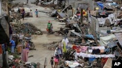 Survivors of Typhoon Haiyan walk amid ruins of their homes in Maraboth, Philippines, Nov. 14, 2013.