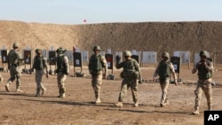 Soldados estadounidenses ayudando a fuerzas de seguridad iraquíes a mejorar sus habilidades de tiro en TAji, al norte de Bagdad, Irak.