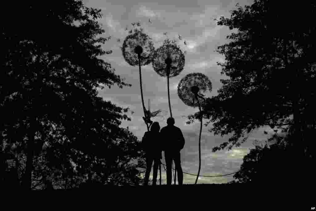 Visitors are silhouetted as they look at "Dandelion Sculpture" by Amy Stoneystreet and Robin Wight at the Royal Horticultural Society Garden Wisley, in the village of Wisley, near Woking, England.