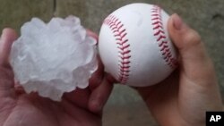 This photo provided by Tim Creedon shows his baseball and a hailstone that fell in the backyard of Creedon's home in Ottawa, Ill., Feb. 28, 2017.
