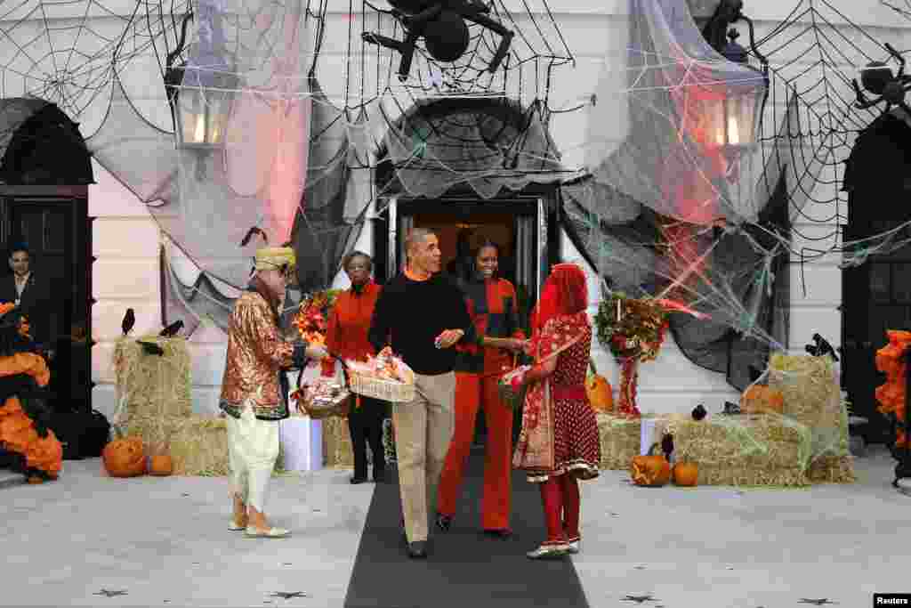 U.S. President Barack Obama (center left) and first lady Michelle Obama (center right) give Halloween treats to visiting children at the White House in Washington, D.C., Oct. 31, 2013.