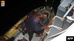 This handout picture released on April 8, 2014 by The Marina Militare shows rescuers of the Italian Navy helping refugees to climb on their boat near the Italian port of Pozzallo, south of Sicily.