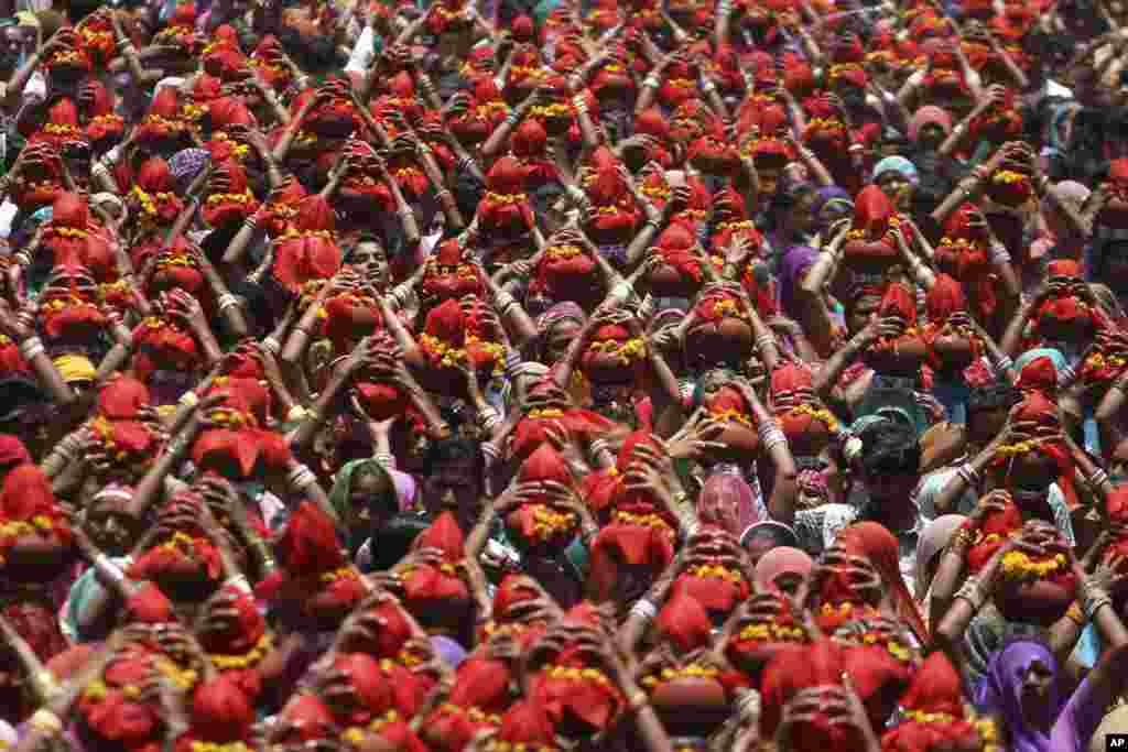 Para perempuan India membawa pot tanah ditutupi dengan kain merah selama prosesi keagamaan lokal disebut Gangaji di kota Ahmadabad.