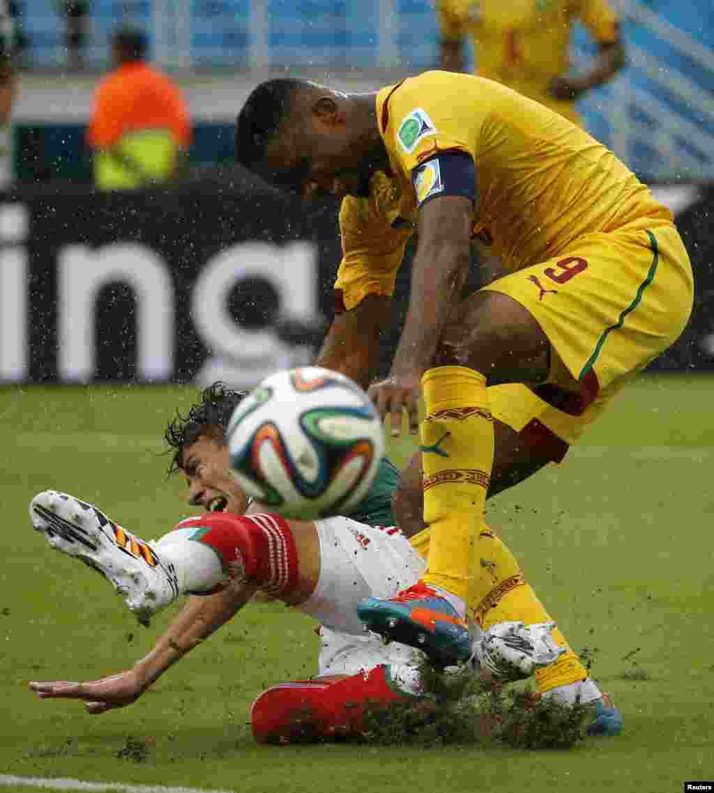 Hector Moreno dari Meksiko (bawah) berebut bola dengan Samuel Eto'o dari Kamerun selama pertandingan Grup A di stadion Dunas di Natal (13/6). (Reuters/Jorge Silva)