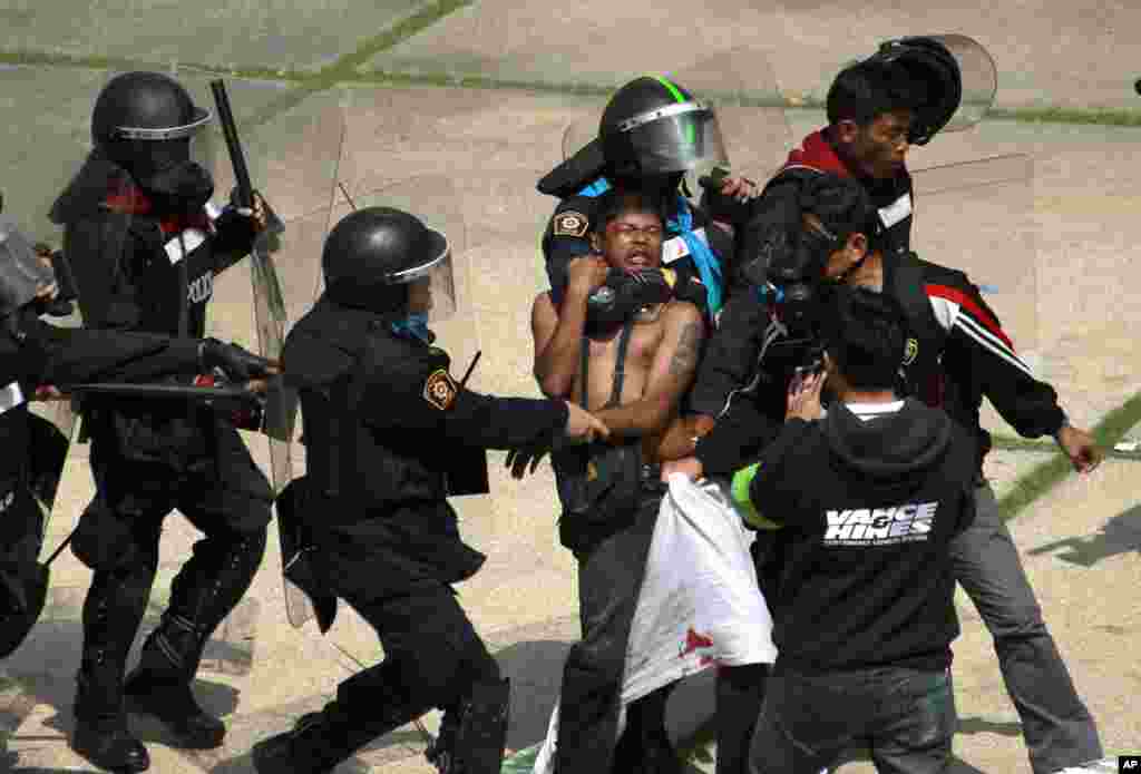An anti-government protester is detained by riot police during a clash at a sports stadium in Bangkok, Thailand. Rock-throwing demonstrators trying to halt preparations for elections fought police in the capital, escalating their campaign to topple the country's beleaguered government.