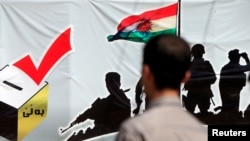 FILE - A man looks at a banner supporting the referendum for independence of Kurdistan in Erbil, Iraq, Sept. 24, 2017.