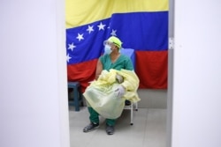 Con una bandera de Venezuela de fondo, un médico espera recibir una dosis de la vacuna rusa COVID-19 Sputnik V en el hospital público Ana Francisca Pérez de León II en Caracas, Venezuela, el viernes 19 de febrero de 2021.