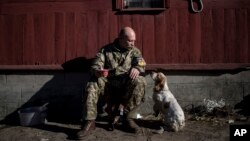 Un militar ucraniano conversa con su perro en la aldea de Luhansk, en el este de Ucrania.