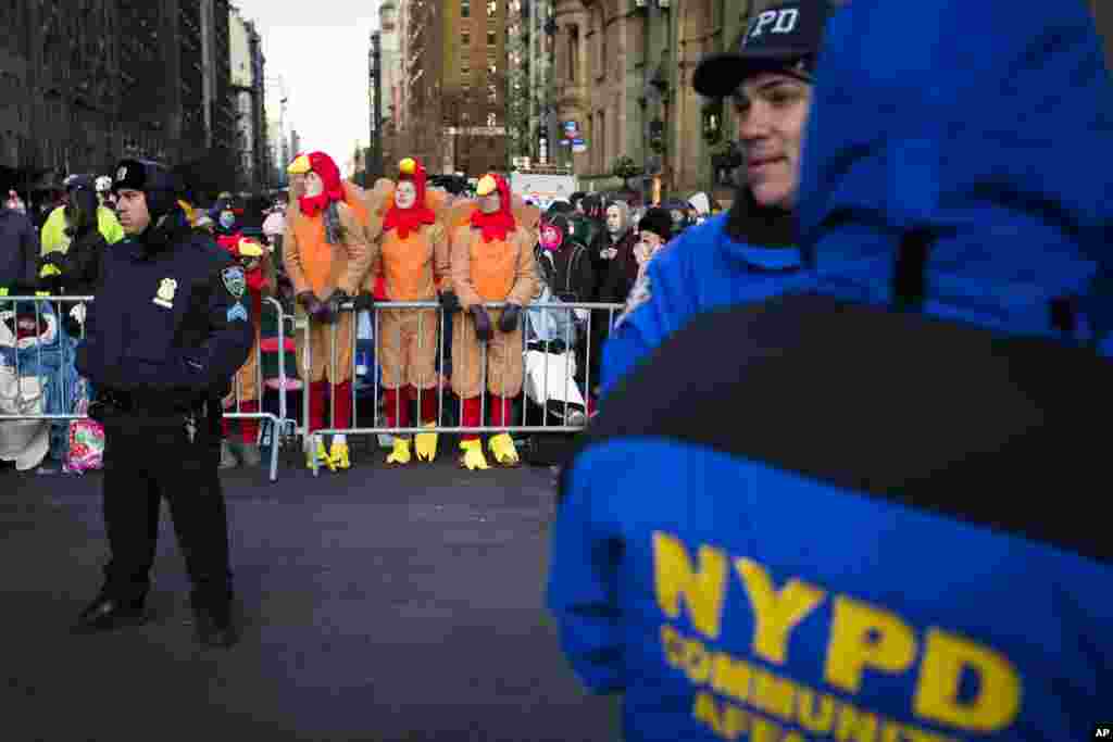 Para penonton memakai kostum kalkum berdiri di belakang barikade polisi saat menunggu Parade Hari Bersyukur Tahunan Macy's ke-87 di New York (28/11). (AP/John Minchillo)