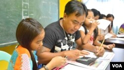 Alvin Balenton, flanked by his two youngest children, attends a class for single fathers coping with life apart from their wives who work overseas, Mabalacat, Pampanga Province, Philippines, Oct. 29, 2014. (VOA / S. Orendain)
