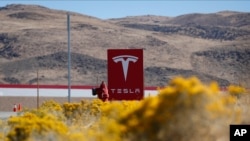 FILE - A sign marks the entrance to the Tesla Gigafactory in Sparks, Nevada, Oct. 13, 2018. Police in Texas are trying to establish whether a Tesla car's driver assistance system was engaged when it crashed, killing to people.