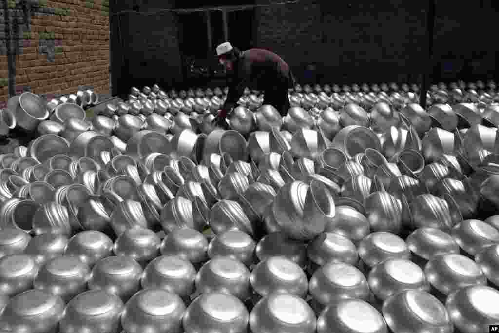 An Afghan laborer arranges pots at an aluminum factory, on Surkh Rod district of Jalalabad east of Kabul, Afghanistan.
