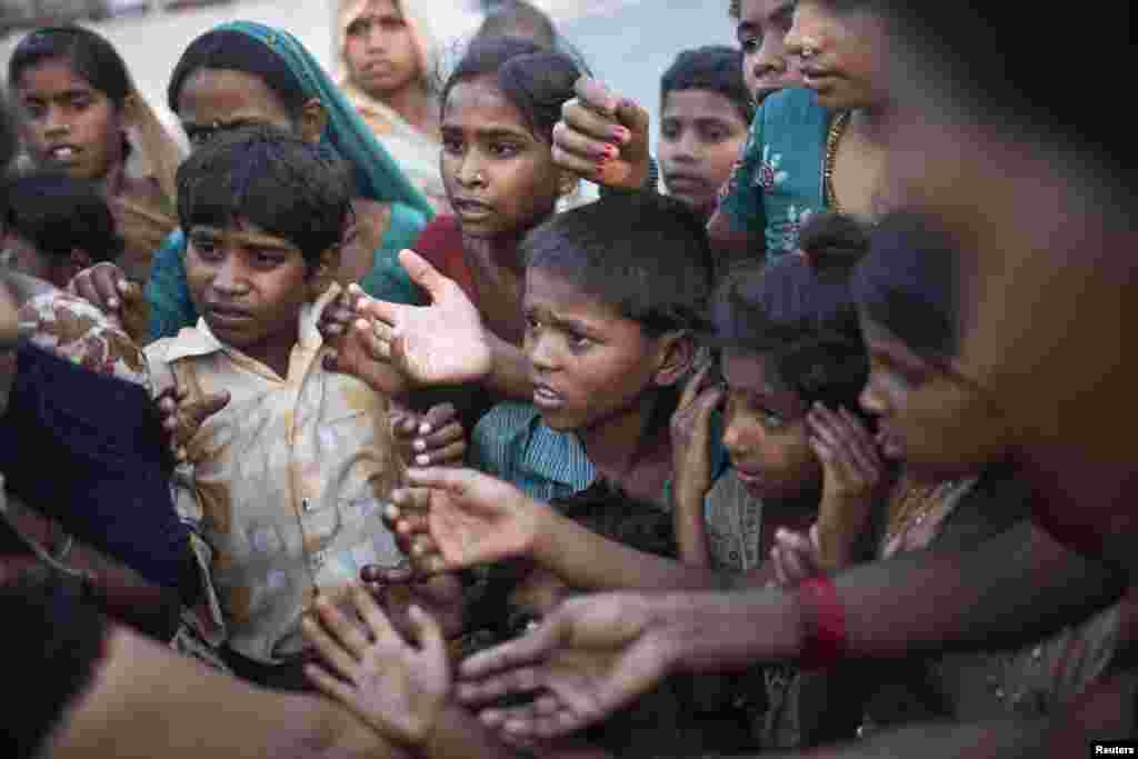 Children displaced by the rising waters of the river Yamuna wait to receive free food distributed by volunteers outside makeshift tents at a roadside camp in New Delhi, India.