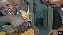 A Sierra Leonean maternal and child health aide administers a vaccine to a child in the village of Sembehun, outside the town of Bo, in the southeast region of the West African country, May 2011