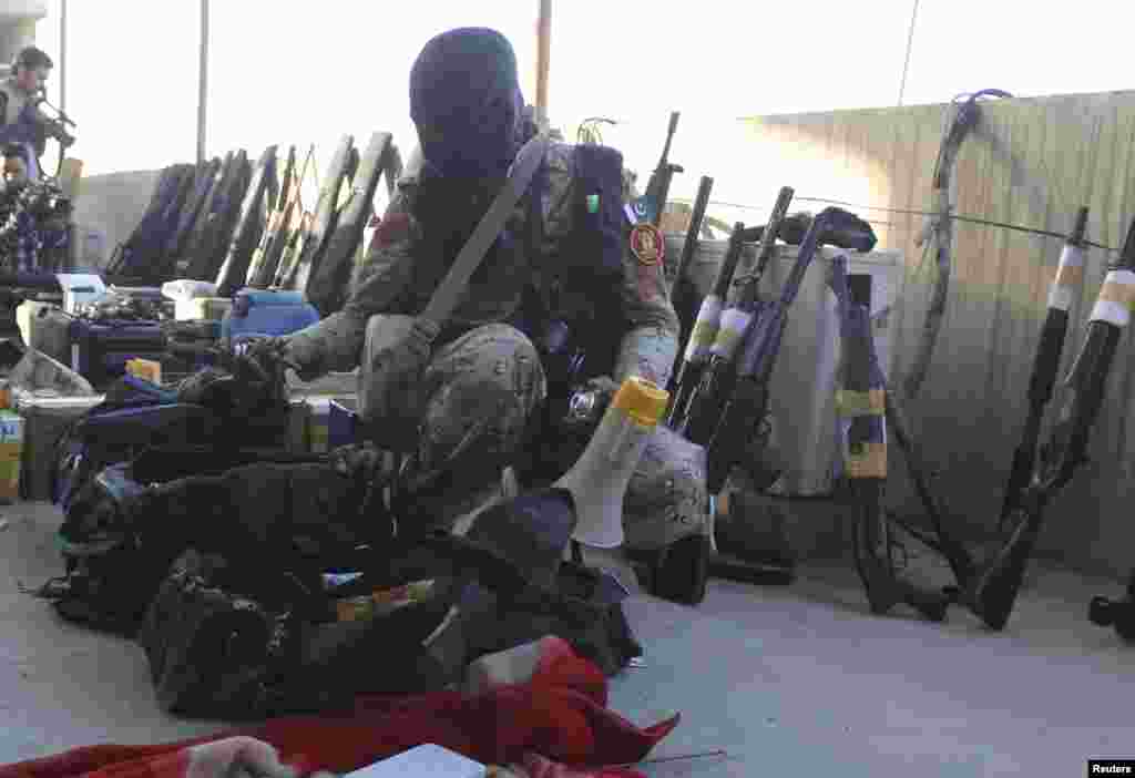 A paramilitary soldier displays weapons recovered during a raid on the Muttahida Qaumi Movement (MQM) political party's headquarters in Karachi, March 11, 2015.