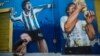 Seorang penggemar, Augusto Canosa, berdoa sambil menyentuh lukisan Diego Maradona dekat stadion Boca Juniors di Buenos Aires, Argentina, 27 November 2020. 