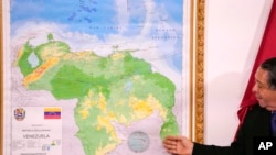 ARCHIVO - El presidente de la Comisión Especial para la Defensa de Guyana Esequibo, Hermann Escarra, junto al nuevo mapa de Venezuela que incluye el territorio de Esequibo, durante una ceremonia de inauguración en Caracas, Venezuela, 8 de diciembre de 2023.