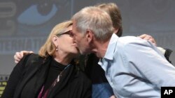 FILE - Carrie Fisher, left, and Harrison Ford kiss at the Lucasfilm's "Star Wars: The Force Awakens" panel on day 2 of Comic-Con International in San Diego, Calif.