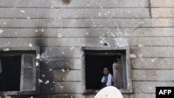 Free Syrian Army fighter looks out from the window of the burnt Shaar district police station in the northern Syrian city of Aleppo after it was overrun by rebel fighters on July 25, 2012. 