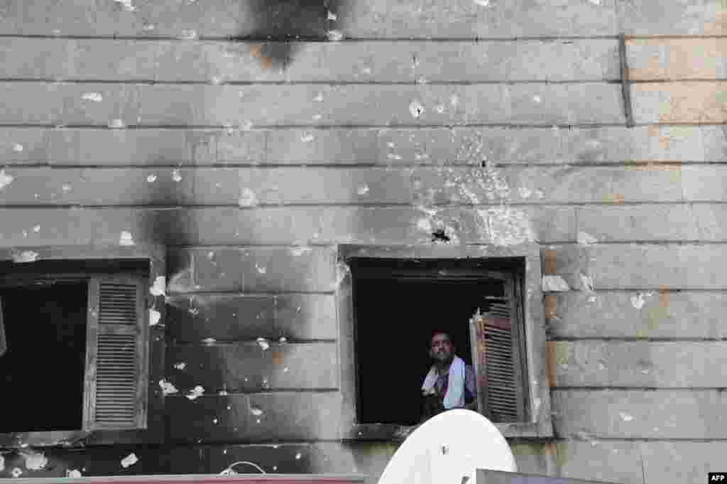 A Free Syrian Army fighter looks out from the window of the Shaar district police station in the northern Syrian city of Aleppo after it was overrun by rebel fighters on July 25, 2012.