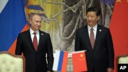 FILE - Russia's President Vladimir Putin (L), and China's President Xi Jinping smile during signing a ceremony in Shanghai, China, May 2014.