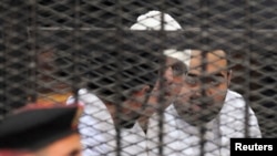 Political activists Ahmed Maher, Ahmed Douma (L) and Mohamed Adel (R) of the April 6 movement look on from behind bars in Abdeen court in Cairo, Egypt, Dec. 22, 2013.