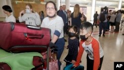 Seorang ibu dan dua anaknya (mengenakan masker) dari Wuhan, China, tiba di bandara Sydney, 23 Januari 2020. (Foto: dok).