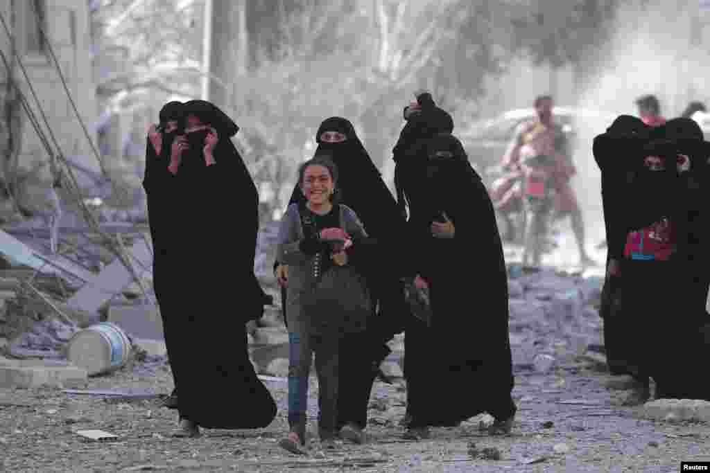 A girl reacts while walking with women after they were evacuated with others by the Syria Democratic Forces (SDF) fighters from an Islamic State-controlled neighborhood of Manbij, in Aleppo Governorate, Syria, Aug. 12, 2016.