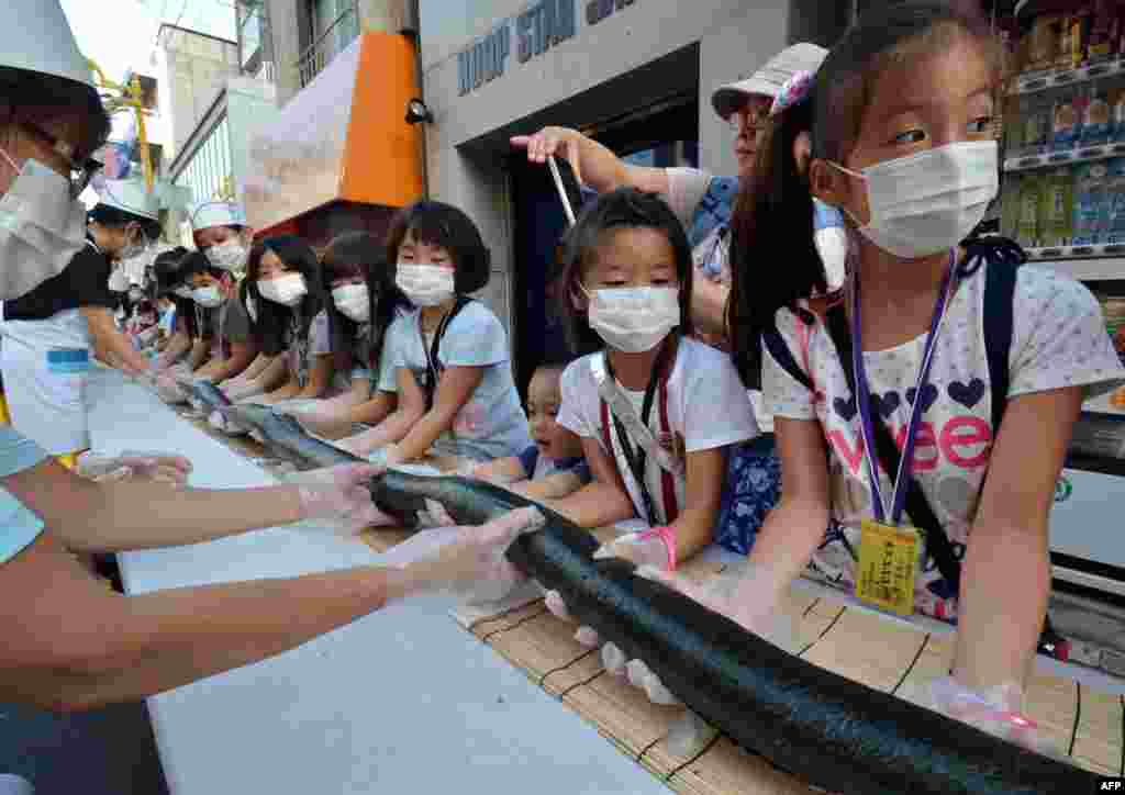 Anak-anak dan relawan membuat sushi sepanjang 120 meter untuk melayani warga setempat di sebuah acara di Tokyo, Jepang.