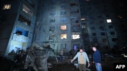 Local residents stand in the courtyard of a damaged residential building following a missile attack in Kharkiv late on Sept. 21, 2024.