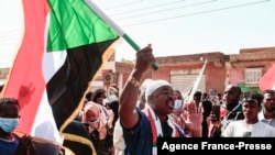 A Sudanese demonstrator waves a national flag as he shouts slogans during a rally against the military chief who launched an Oct. 25 coup followed by a bloody crackdown, in the northern part of Khartoum, Dec. 19, 2021.
