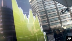 FILE - Pedestrians are reflected in an electronic stock chart showing Japan's Nikkei 225 at a securities firm in Tokyo, Feb. 9, 2016.