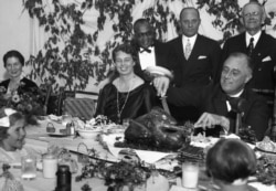 President Franklin D. Roosevelt carves the turkey during Thanksgiving dinner for polio patients at Warm Springs, Ga., with first lady Eleanor Roosevelt beside him, Dec. 1, 1933.