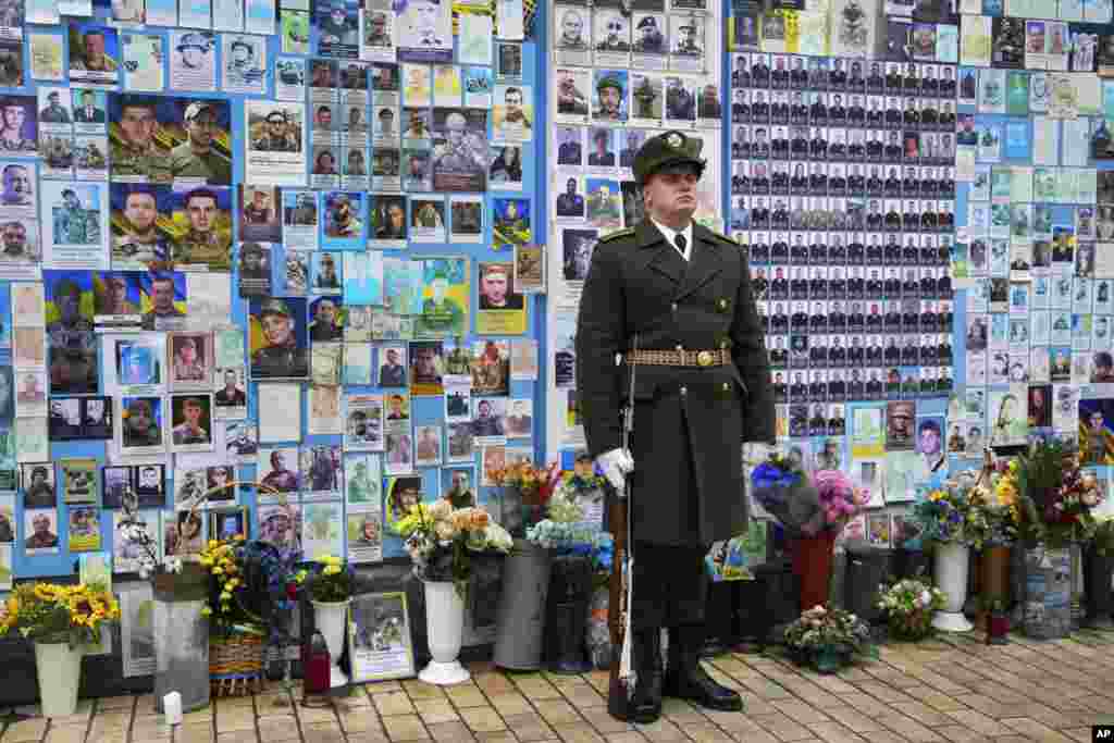 A soldier stands in front of The Wall of Remembrance of the Fallen for Ukraine at St Michael's Square in Kyiv, Ukraine.