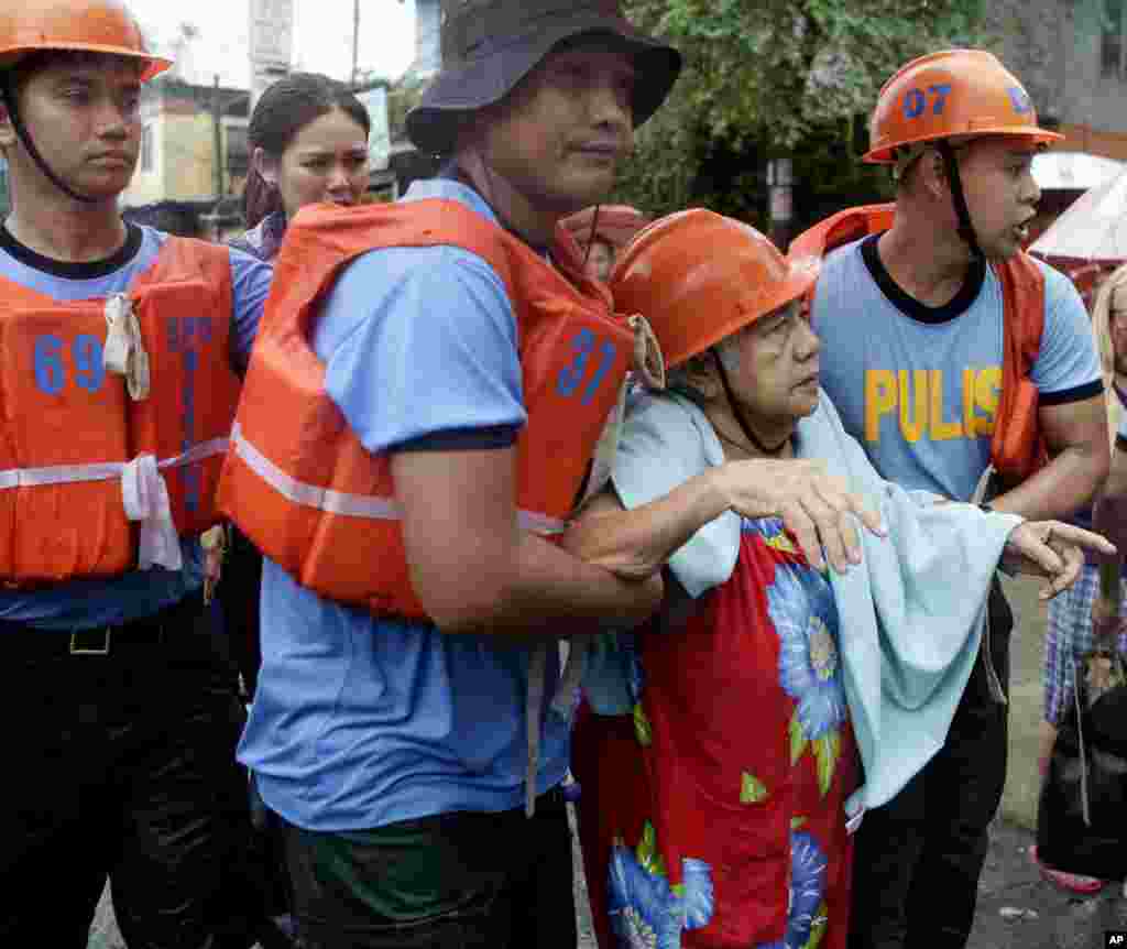 Philippine National Police officers help a resident to a waiting police truck as they enforce an evacuation following the swelling of Marikina River in Marikina city, east of Manila, August 20, 2013.