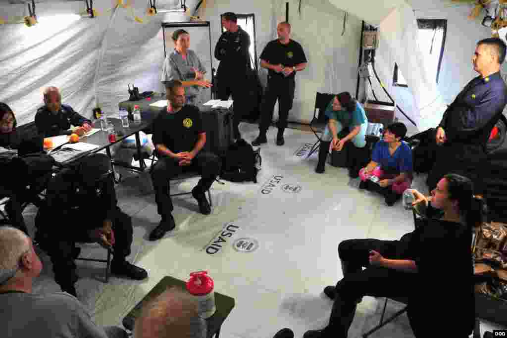 Personnel from the U.S. Public Health Service during a meeting in the staff reporting tent of the Monrovia Medical Unit, near Monrovia, Liberia, Nov. 4, 2014. (Sgt. 1st Class Nathan Hoskins/DOD)