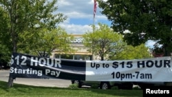 FILE - : A banner inviting people to apply for open jobs is seen outside a McDonald's restaurant in Bloomington, Indiana, May 14, 2021.