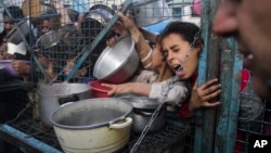 FILE - Palestinians line up to receive free meals at Jabaliya refugee camp in the Gaza Strip on Monday, March 18, 2024. (AP Photo/Mahmoud Essa)