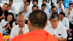 Former Vice President of opposition party Cambodia National Rescue Party (CNRP) Pol Ham, center left, prays Buddhist monks, foreground, together with his former party lawmaker Son Chhay, center right, during a Buddhist ceremony, in Phnom Penh, Cambodia, F