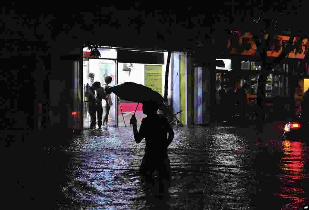 A man wades through a flooded street following a heavy rain in Beijing, China, July 21, 2012.