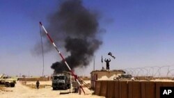 This image posted on a militant news Twitter account on June 12, 2014 shows militants from the al-Qaida-inspired Islamic State, formerly known as the Islamic State in Iraq and the Levant (ISIL), raising their flag at an army base in Ninevah Province, Iraq.