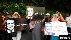 FILE - Supporters of presidential candidate Nabil Karoui, hold his pictures as they take part in a rally asking for his release from prison, in front of the courthouse in Tunis, Tunisia, Sept. 3, 2019. 