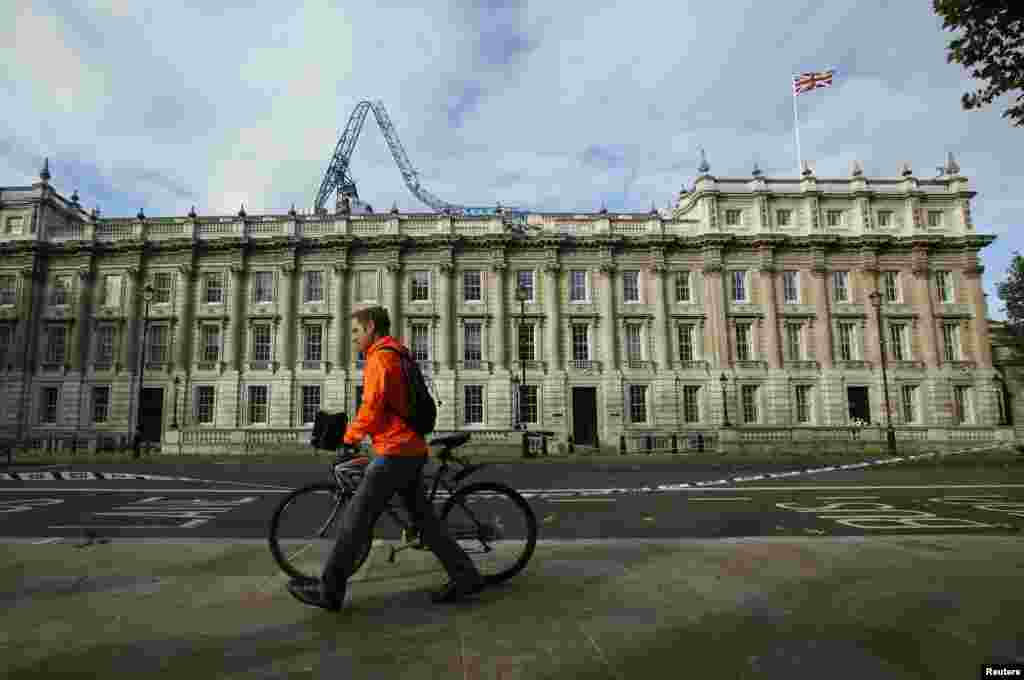 Seorang pria mendorong sepedanya melewati kantor Kabinet yang atapnya ditimpa derek di London (28/10).